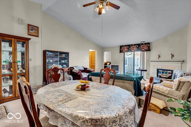 carpeted dining space with a textured ceiling, high vaulted ceiling, and ceiling fan