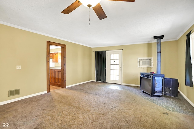 unfurnished living room with ceiling fan, a wall mounted air conditioner, a wood stove, ornamental molding, and carpet