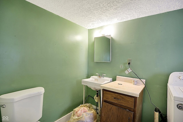 bathroom with a textured ceiling, sink, toilet, and washer / dryer