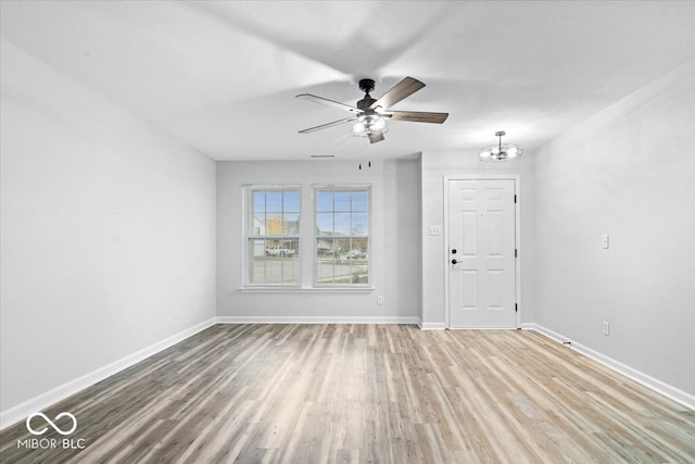 empty room with ceiling fan with notable chandelier and hardwood / wood-style floors