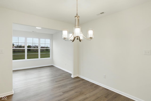 unfurnished dining area with a chandelier and dark hardwood / wood-style flooring