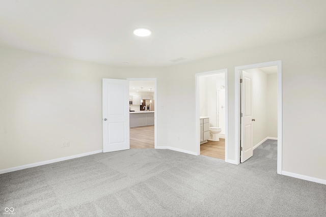 unfurnished bedroom featuring light carpet, stainless steel fridge, and connected bathroom