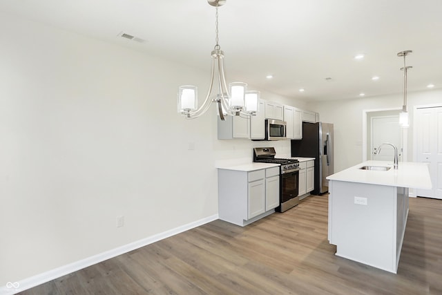 kitchen with pendant lighting, sink, stainless steel appliances, and a center island with sink