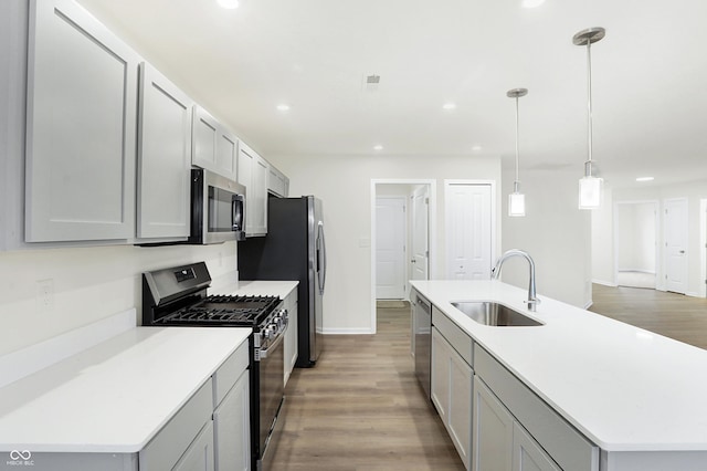 kitchen with gray cabinetry, stainless steel appliances, sink, hardwood / wood-style floors, and hanging light fixtures