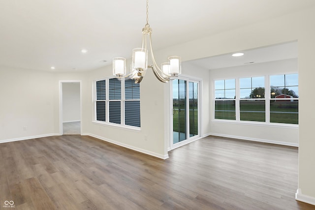 unfurnished dining area featuring wood-type flooring and an inviting chandelier