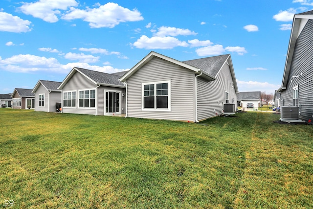 rear view of property featuring central AC unit and a lawn