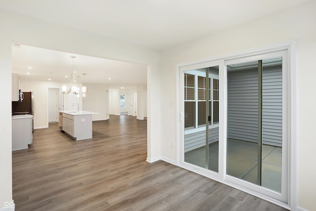 kitchen featuring hardwood / wood-style floors, sink, an island with sink, and hanging light fixtures