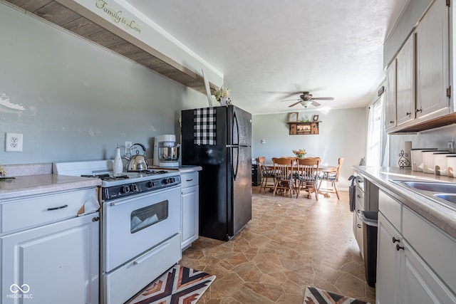 kitchen with white cabinetry, ceiling fan, black fridge, and gas range gas stove