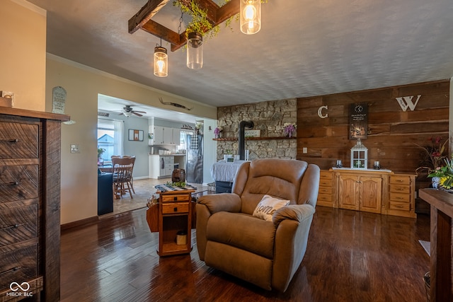 sitting room with ceiling fan, wooden walls, a wood stove, dark hardwood / wood-style floors, and ornamental molding