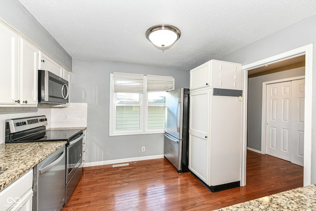 kitchen featuring light stone countertops, white cabinets, dark hardwood / wood-style flooring, appliances with stainless steel finishes, and tasteful backsplash