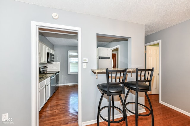 kitchen with a textured ceiling, white cabinets, dark hardwood / wood-style floors, and electric stove