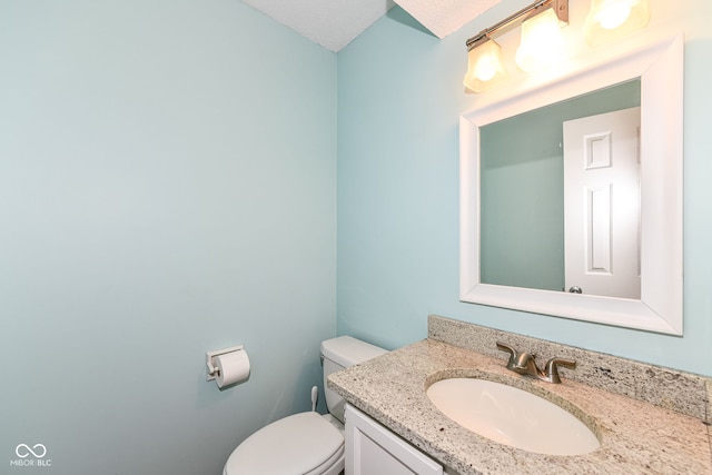 bathroom featuring vanity, a textured ceiling, and toilet