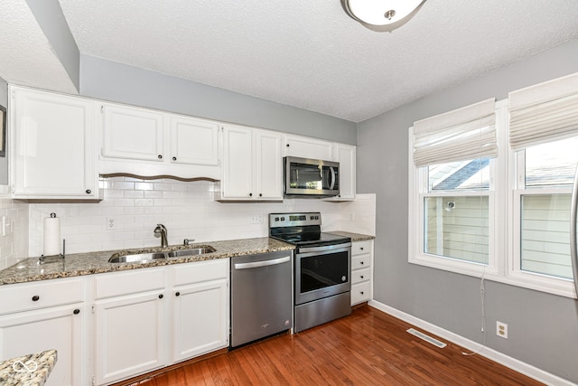 kitchen with white cabinetry, appliances with stainless steel finishes, and dark hardwood / wood-style floors