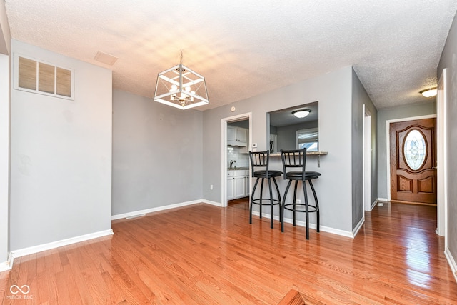 interior space featuring sink, a textured ceiling, an inviting chandelier, and hardwood / wood-style floors