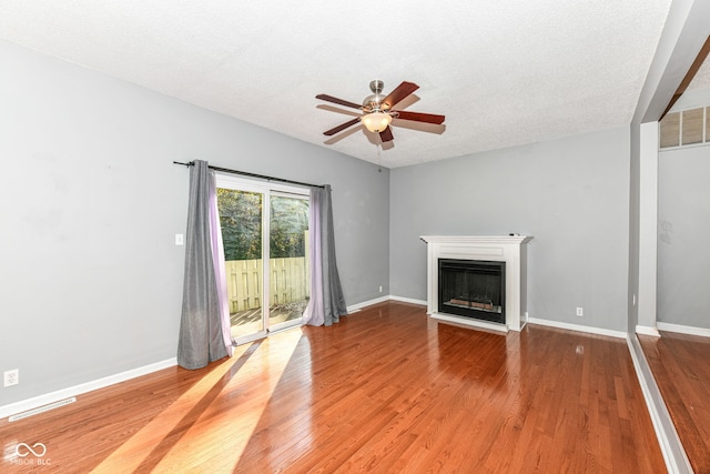 unfurnished living room featuring ceiling fan, hardwood / wood-style flooring, and a textured ceiling