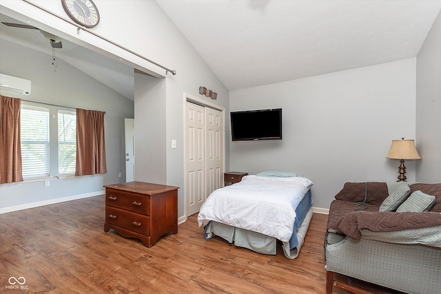 bedroom featuring vaulted ceiling, hardwood / wood-style floors, ceiling fan, a closet, and a wall mounted air conditioner