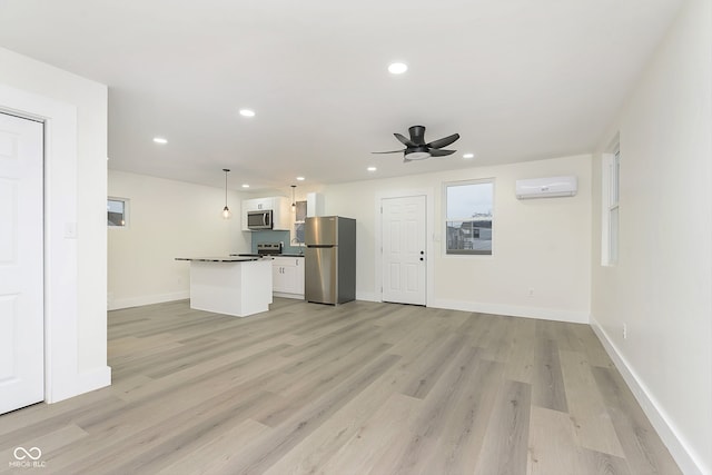 unfurnished living room featuring light hardwood / wood-style floors, an AC wall unit, and ceiling fan