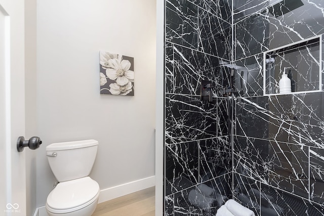 bathroom featuring tiled shower, hardwood / wood-style flooring, and toilet