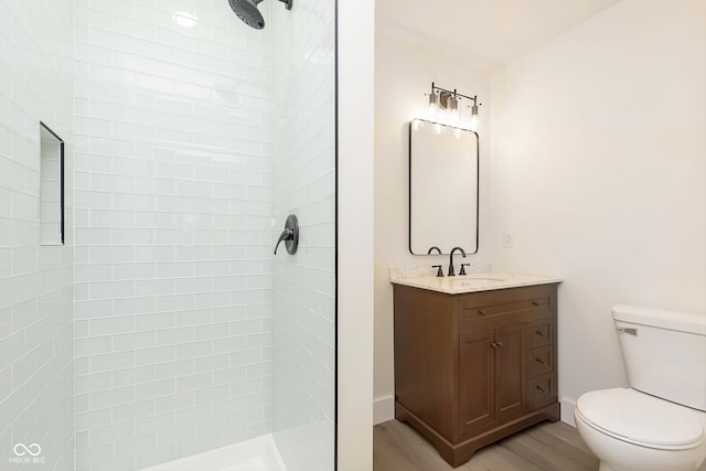 bathroom featuring tiled shower, hardwood / wood-style floors, vanity, and toilet