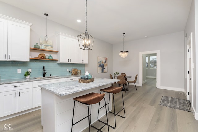 kitchen with sink, an inviting chandelier, light hardwood / wood-style flooring, white cabinetry, and a breakfast bar area