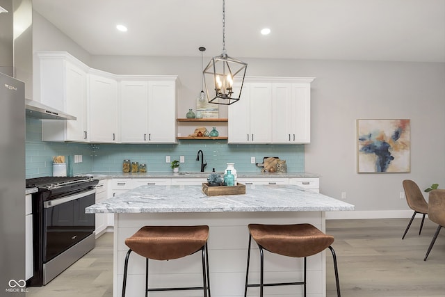 kitchen with stainless steel electric stove, a kitchen island, white cabinets, and light wood-type flooring