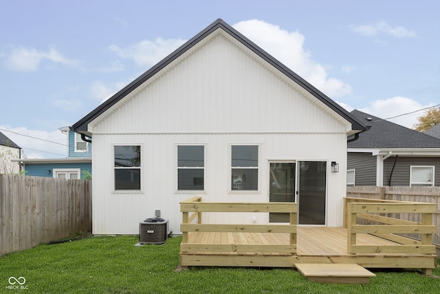 back of property with a deck, central AC unit, and a lawn