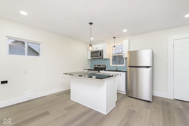 kitchen with light hardwood / wood-style flooring, white cabinets, pendant lighting, and appliances with stainless steel finishes