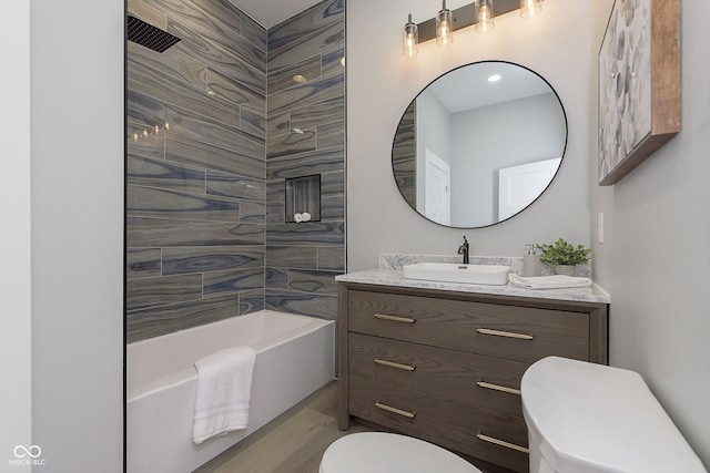 full bathroom with tiled shower / bath, vanity, and toilet