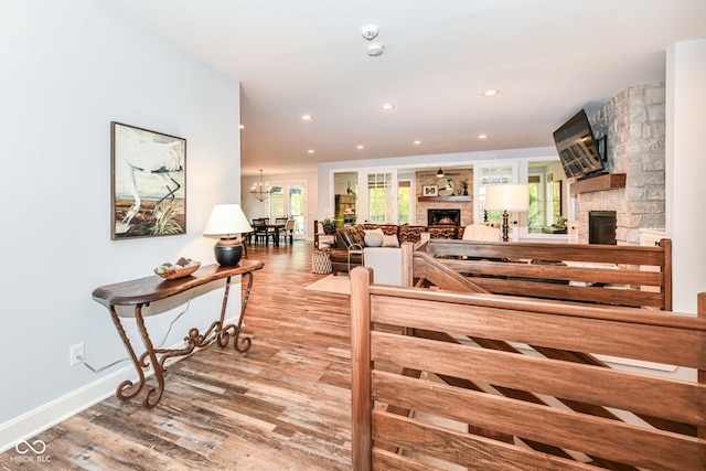 living room featuring a notable chandelier, a stone fireplace, and hardwood / wood-style flooring