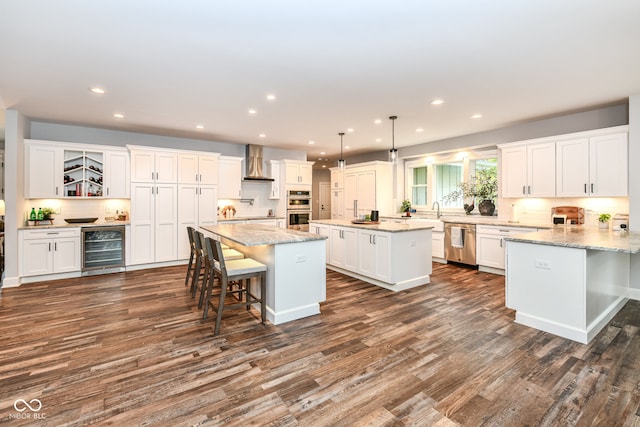 kitchen with wall chimney range hood, appliances with stainless steel finishes, dark hardwood / wood-style flooring, wine cooler, and a breakfast bar area