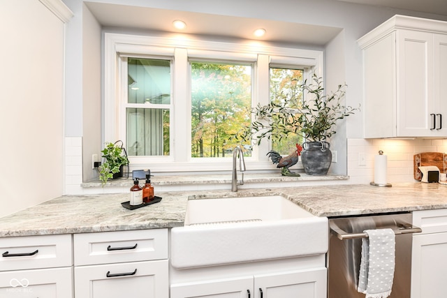 kitchen with dishwasher, sink, light stone countertops, white cabinetry, and tasteful backsplash