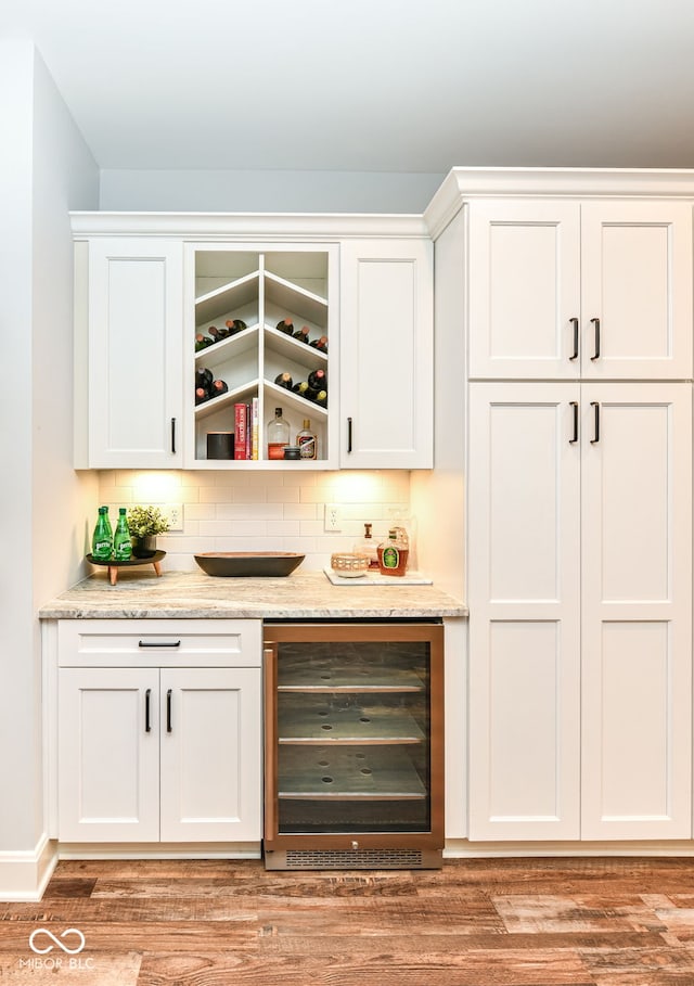 bar with white cabinetry, tasteful backsplash, light wood-type flooring, and beverage cooler