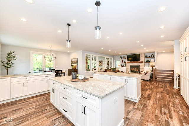 kitchen with white cabinets, a kitchen island, dark hardwood / wood-style floors, a fireplace, and decorative light fixtures