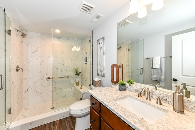 bathroom featuring vanity, toilet, wood-type flooring, and a shower with shower door