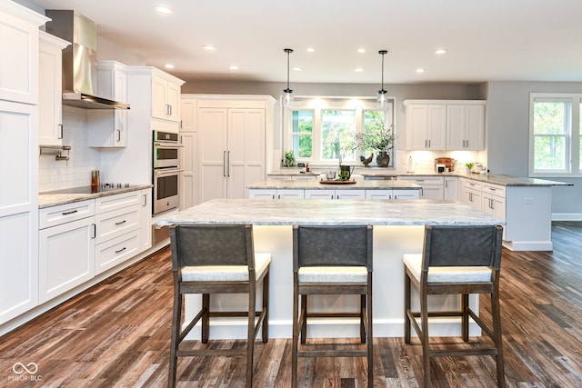 kitchen with dark hardwood / wood-style flooring, a center island, decorative light fixtures, and plenty of natural light