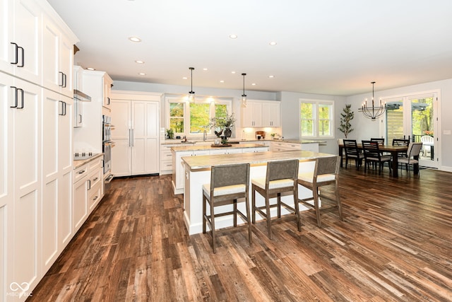 kitchen with a wealth of natural light, pendant lighting, a kitchen island, and dark hardwood / wood-style flooring