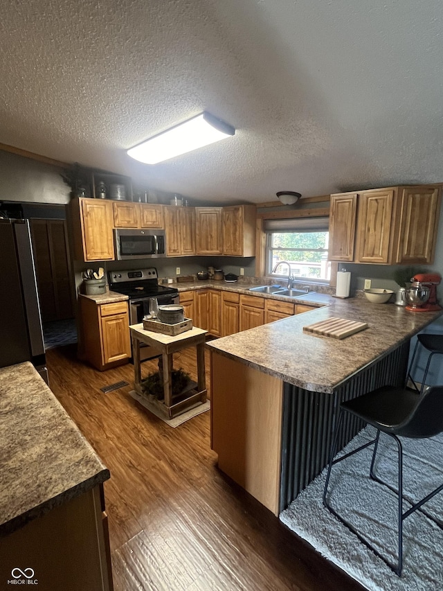 kitchen with dark wood-type flooring, refrigerator, black / electric stove, a kitchen bar, and kitchen peninsula