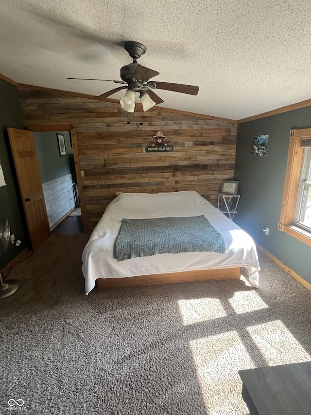 carpeted bedroom with ceiling fan, a textured ceiling, wooden walls, and vaulted ceiling