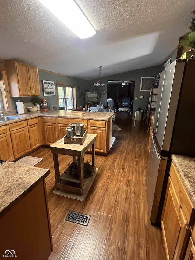 kitchen featuring lofted ceiling, dark wood-type flooring, stainless steel fridge, a textured ceiling, and kitchen peninsula