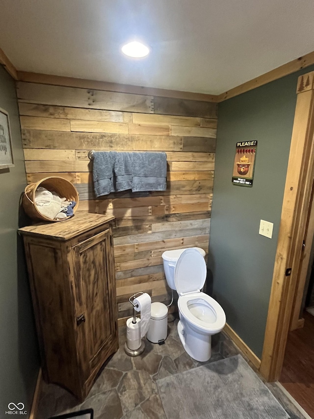 bathroom with ornamental molding, toilet, and wooden walls