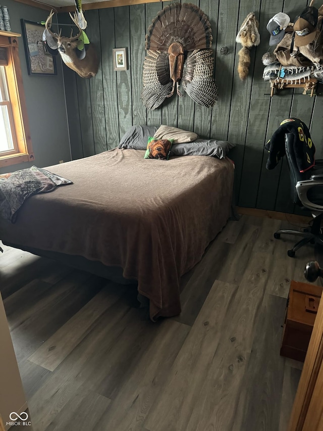 bedroom with hardwood / wood-style floors and wooden walls