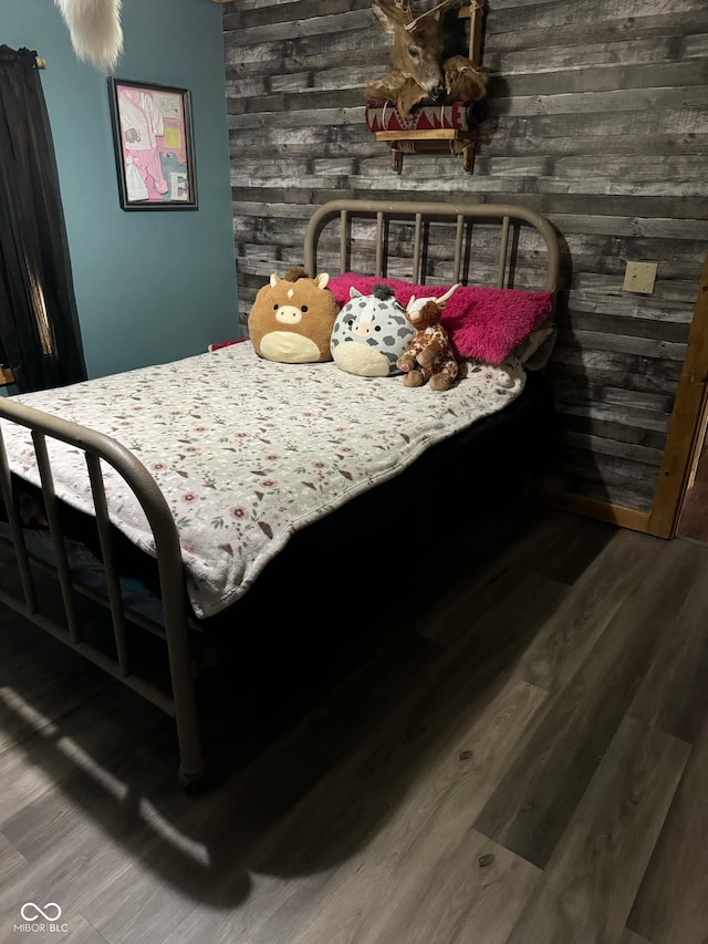 bedroom featuring wood-type flooring and wood walls