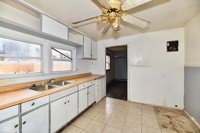 kitchen featuring light tile patterned flooring, wood counters, sink, and white cabinetry