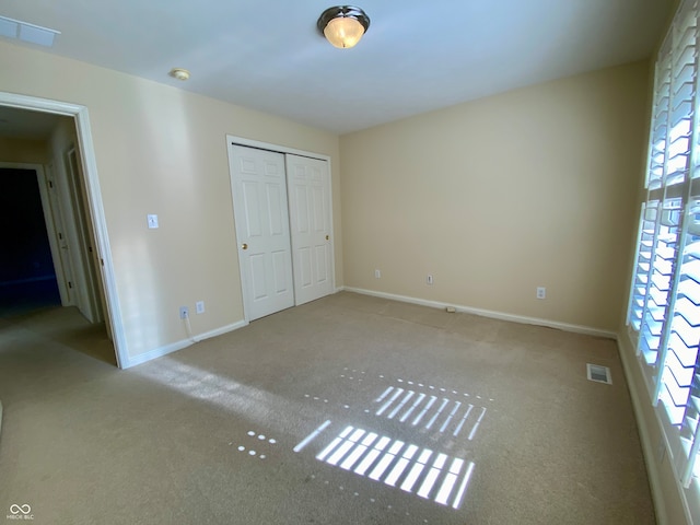 unfurnished bedroom with a closet and light carpet