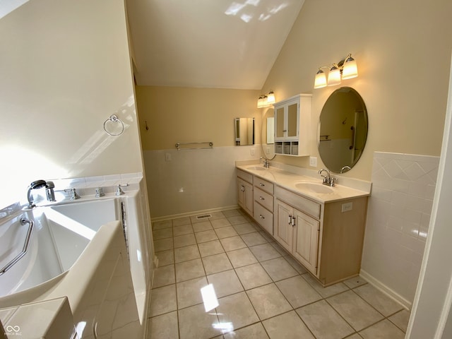 bathroom with vanity, lofted ceiling, a tub to relax in, and tile patterned floors