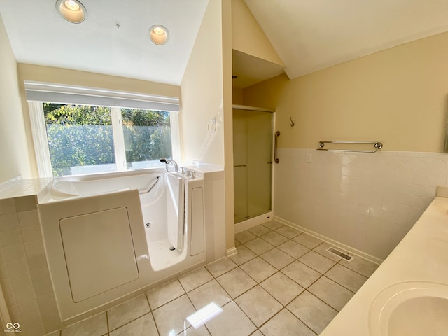 bathroom with independent shower and bath, vaulted ceiling, tile patterned flooring, and tile walls