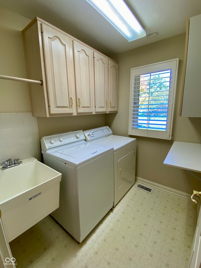 washroom with sink, washer and dryer, and cabinets