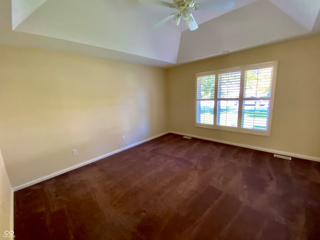 unfurnished room featuring dark colored carpet, a tray ceiling, and ceiling fan