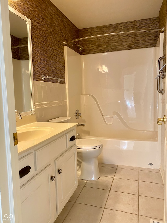 full bathroom featuring toilet, tile patterned flooring, vanity, tile walls, and washtub / shower combination