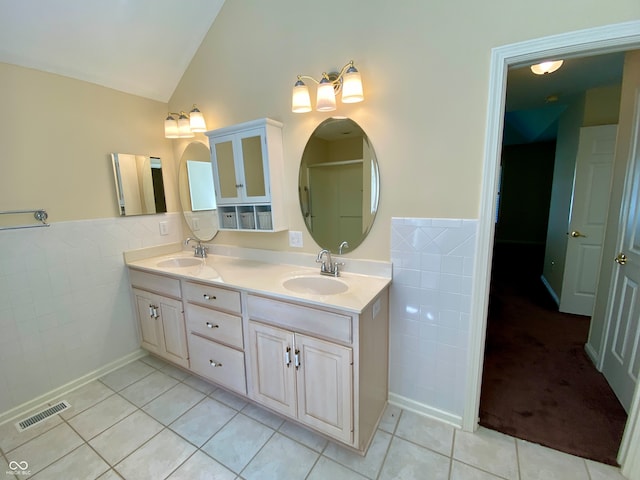 bathroom with vanity, lofted ceiling, tile patterned floors, and tile walls